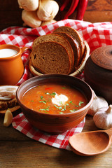 Ukrainian beetroot soup - borscht in bowl and pot, on napkin, on wooden background