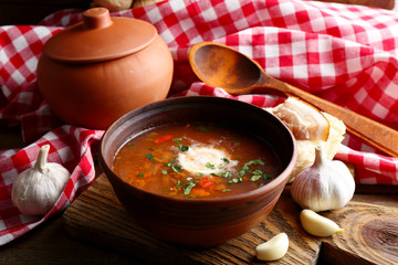 Ukrainian beetroot soup - borscht in bowl and pot, on napkin, on wooden background