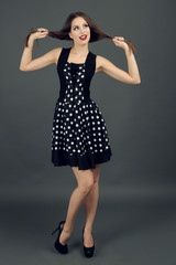 Beautiful young woman in dots dress on dark gray background