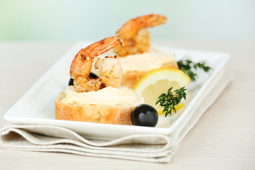 Appetizer canape with shrimp and olives on table on light background