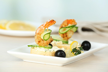 Appetizer canape with shrimp and olives on table on light background