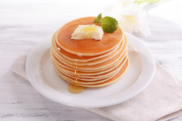 Delicious pancakes with honey on plate on table close-up