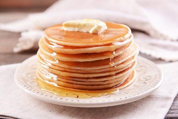 Delicious pancakes with honey on plate on table close-up