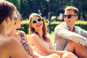 group of smiling friends outdoors sitting in park