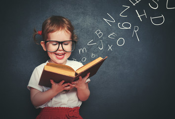 little girl with glasses reading a book with departing letters