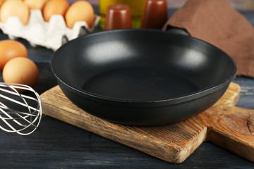 Still life with eggs and pan on wooden background
