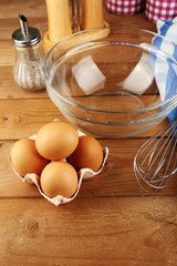 Preparation cream with eggs in glass bowl on wooden background