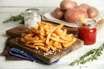 Tasty french fries on cutting board, on wooden table background
