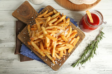 Tasty french fries on cutting board, on wooden table background © Africa Studio
