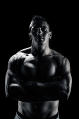 Obraz na płótnie Canvas Low light portrait of bodybuilder over black background