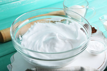 Fototapeta na wymiar Whipped egg whites for cream on color wooden background