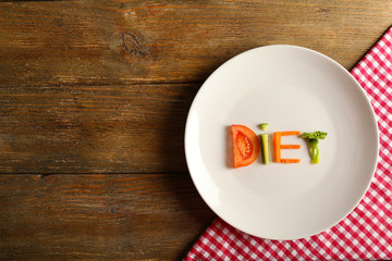 Word DIET made of sliced vegetables in white plate with napkin