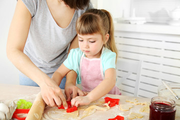 Little girl preparing cookies in kitchen at home