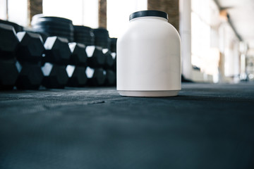 Plastic container with sports nutrition on dumbbells