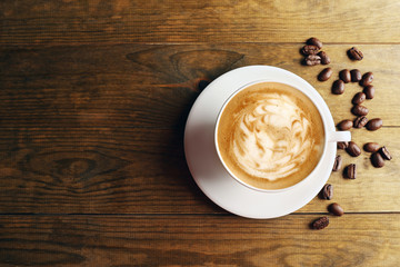 Cup of coffee latte art with grains on wooden background