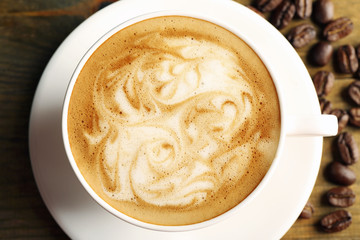 Cup of coffee latte art with grains on wooden table, top view