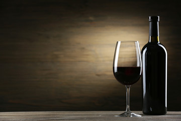 Wineglass and bottle on wooden background