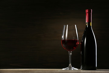 Fototapeta na wymiar Wineglass and bottle on wooden background