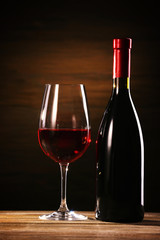 Wineglass and bottle on wooden background
