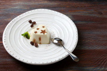 Tasty panna cotta dessert on plate, on wooden table