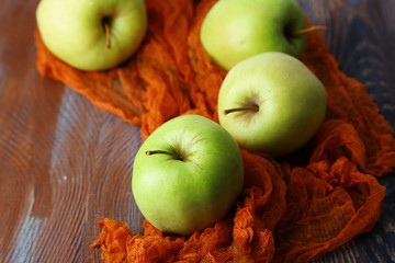 Green apples on wooden table on fabric, closeup