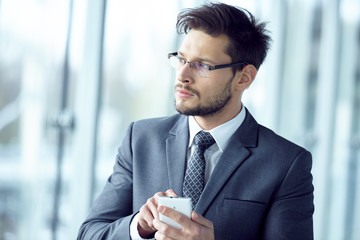 Portrait of a  young businessman in suit standing at office