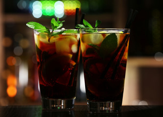 Glass of cocktail in bar on bright blurred background