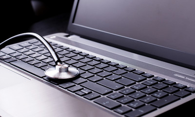 Stethoscope resting on a computer keyboard - concept for online