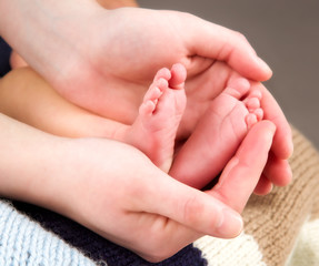 Obraz na płótnie Canvas leg newborn little baby in the mother's hands