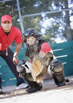 Multi-ethnic baseball catcher and coach behind home plate