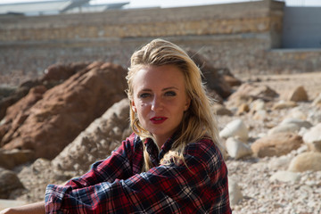 Girl in flannel shirt on the rocky beach.