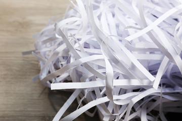 Strips of destroyed paper from shredder on wooden table,