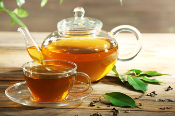 Cups of green tea on table on green background