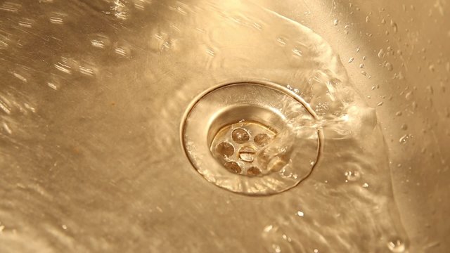 View of a kitchen sink with flowing water and flush