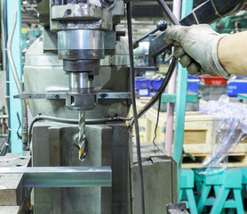Industrial worker drilling a hole on a metal bar by drill machin