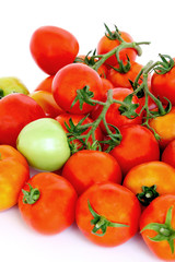 Group of red tomatoes with one green on white background.