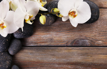 Spa stones and orchid flower on wooden background