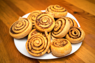 cinnamon rolls on a white dish in a wooden table