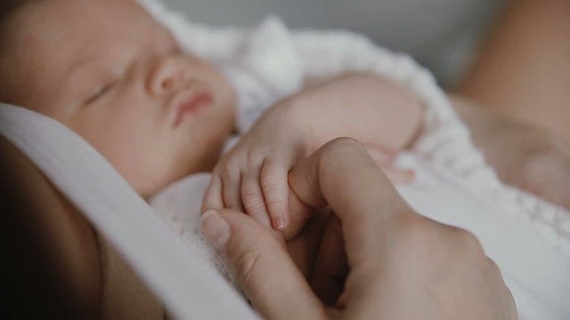 newborn baby hand holding adult finger