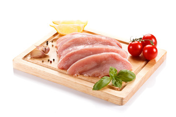 Raw chicken breasts on cutting board on white background