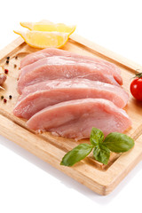 Raw chicken breasts on cutting board on white background