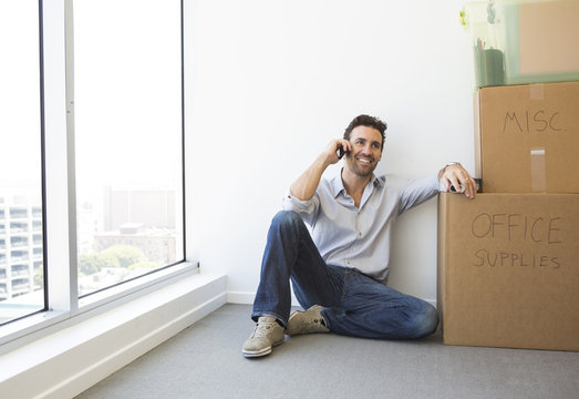 Hispanic businessman on cell phone in new office