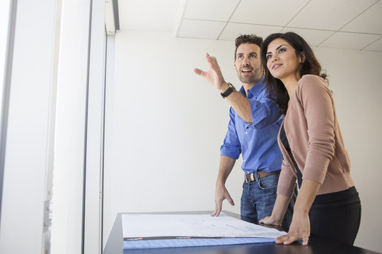 Business people examining blueprints in office - Powered by Adobe