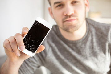 Sad man showing crashed mobile phone