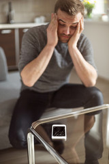 Worried man looking at broken smart phone