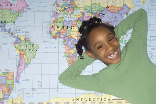 African girl laying on world map