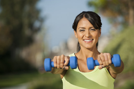 Hispanic woman lifting weights outdoors