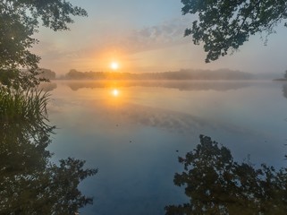 Beautiful sunrise over misty lake.