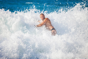 Young man bathing in storming sea, water in focus