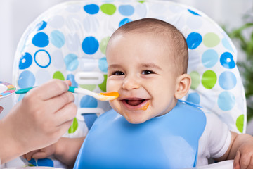 Smiling happy adorable baby eating fruit mash © didesign